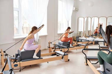 Spor giyinen atletik kadınlar birlikte spor salonunda pilates yapıyorlar..