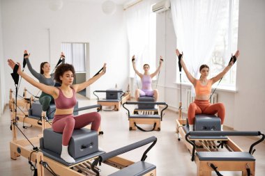 Spor salonunda pilates dersi sırasında zarif bir şekilde egzersiz yapan bir grup kadın..