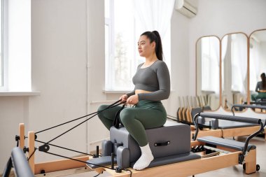 Hoş giyimli çekici kadın aktif olarak pilates dersinde egzersiz yapıyor..