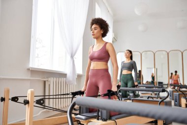 Bir grup güzel spor kadını pilates dersi sırasında çeşitli spor aletleriyle egzersiz yapıyorlar..