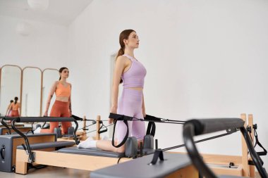 Athletic women gracefully practicing pilates in a gym together. clipart