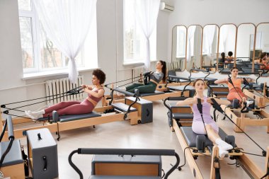 Spor salonunda pilates dersi sırasında zarif bir şekilde egzersiz yapan bir grup kadın..