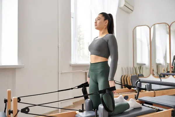 stock image Young woman in comfy sportswear practising during pilates lesson.