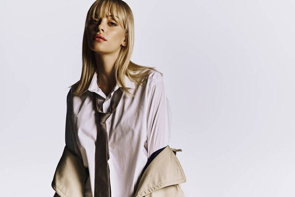 Stylish woman poses confidently in tie on white backdrop.