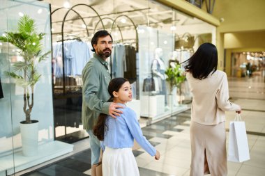 Bir adam ve kızı, mutlu bir aile haftasonu gezisinde kalabalık bir alışveriş merkezinde rahatça dolaşırlar..