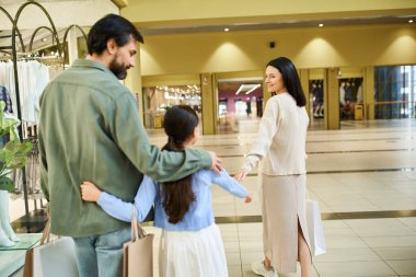 Mutlu bir anne ve kızı alışveriş merkezinde alışveriş yaparken çeşitli eşya ve dükkanlara bakıyorlar..