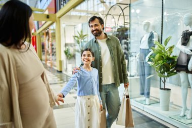 Bir erkek ve bir kadın alışveriş çılgınlığının keyfini çıkarırken, hafta sonları alışveriş merkezlerinde çocuklarla rahatça yürürler..