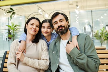 A cheerful family takes a break on a bench while enjoying a shopping outing together in a store. clipart