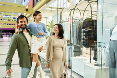 A happy family, parents and children, leisurely walk through a vibrant shopping mall full of shops, people, and colorful displays. clipart