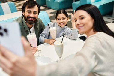 Neşeli bir aile bir restoranda selfie çeker. Hafta sonu birlikte iyi vakit geçirir ve bağrına basar..