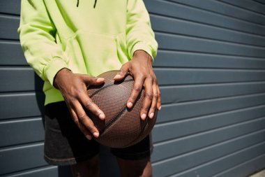 Duvara basketbol topu tutan şık giyimli Afro-Amerikan erkek..
