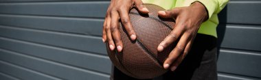 Elinde basketbol topuyla şık giyinmiş Afro-Amerikan bir adam..
