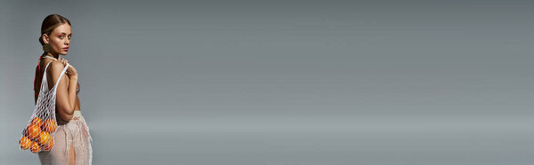 Женщина в белом сари грациозно стоит на сером фоне.