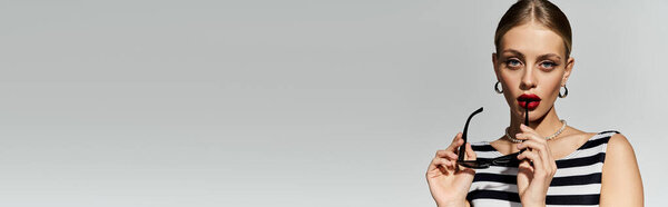 Stylish blonde woman in striped swimsuit striking a pose.