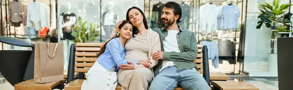 stock image A man and woman relax on a bench with kid in a busy shopping mall, taking a break from their shopping excursion.