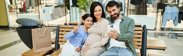 Stock image A cheerful family sits on a bench in a bustling shopping mall, creating memories together on a fun weekend outing.