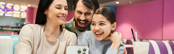 A happy family sitting at a table in a modern restaurant, enjoying a meal and spending quality time together during the weekend.