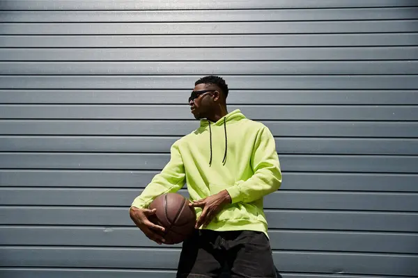 stock image Stylish, African American man in neon hoodie holding basketball.