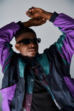 Mor ceketli ve güneş gözlüklü yakışıklı bir adam poz veriyor..