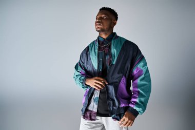 Beyaz bir arka planda parlak ceketli modaya uygun Afrikalı Amerikalı bir adam..