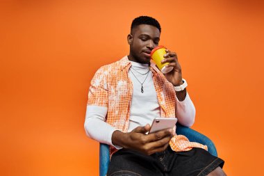 Handsome African American man sitting, holding coffee cup. clipart