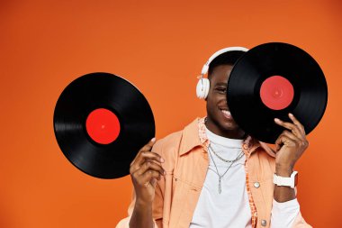 Handsome black man holding two vinyl records in front of him. clipart