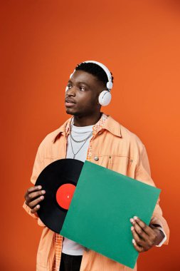 Stylish African American man with headphones holding a vinyl record. clipart