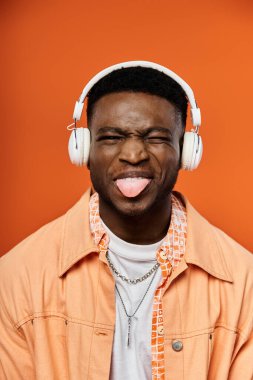 Zevkli ve eğlenceli bir jest yapmak için kulaklık takan Afro-Amerikan bir adam..