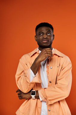Turuncu ceketli yakışıklı adam düşünceli bir poz veriyor..