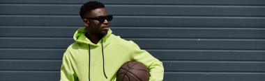Yeşil kapüşonlu yakışıklı Afro-Amerikan adam basketbol oynuyor..