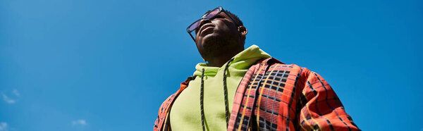 Handsome African American man in stylish attire staring up at the sky.