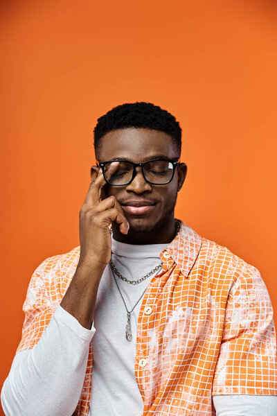 Модный молодой афроамериканец в очках и оранжевой рубашке.