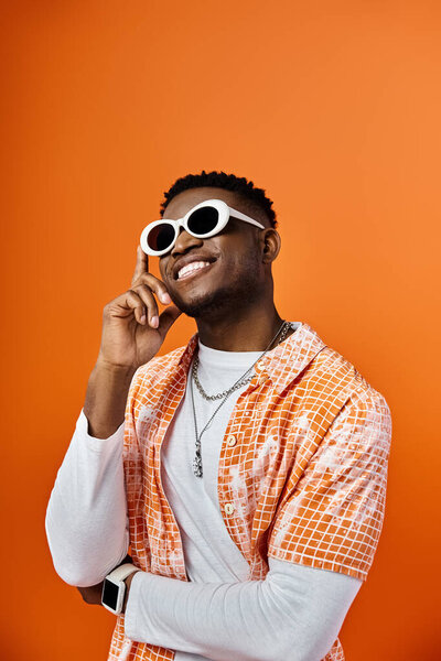 Афроамериканец в солнечных очках на оранжевом фоне.