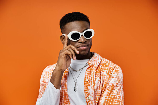 African American man in stylish sunglasses on orange background.