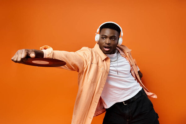 Красивый черный мужчина, стильно одетый, держит пластинку в наушниках.