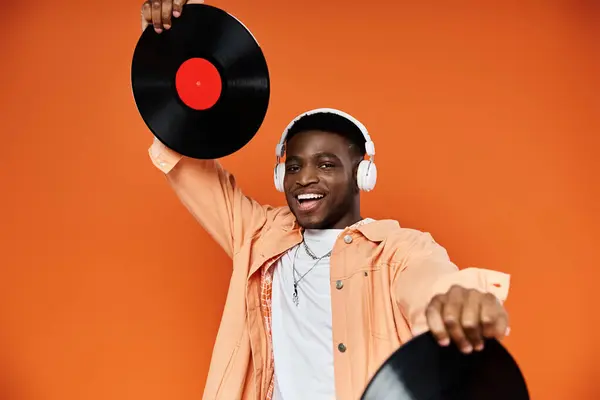 stock image Young black man in stylish attire holding up a vinyl record.