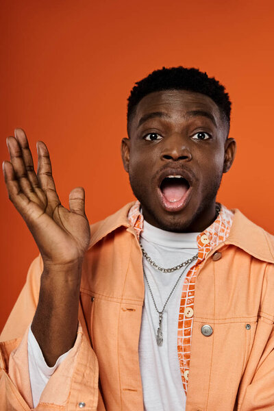 Young African American in orange shirt, mouth open.