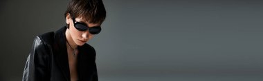 A woman in a black jacket and sunglasses exudes cool confidence.