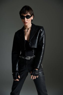 Confident woman in a black leather jacket strikes a pose.