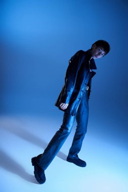 A stylish woman poses confidently in front of a vibrant blue backdrop.