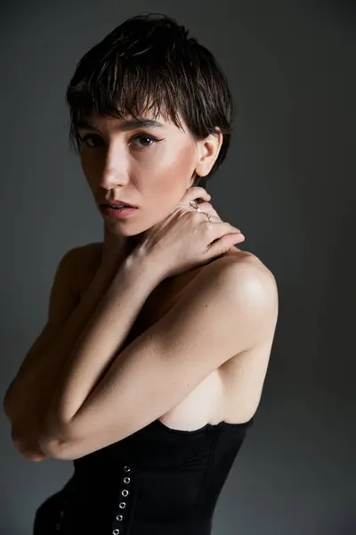 stock image A young woman with striking style poses in a black corset.