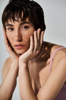A young woman striking a thoughtful pose with hands on face.