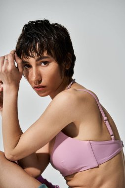 Young woman confidently poses in pink bikini with hands on hips.