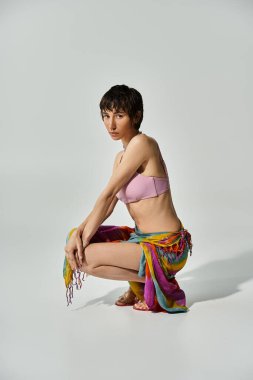 Young woman in colorful bikini crouching on the floor.