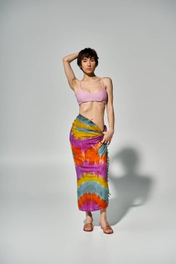 Stylish young woman posing elegantly in a colorful tie dye skirt.