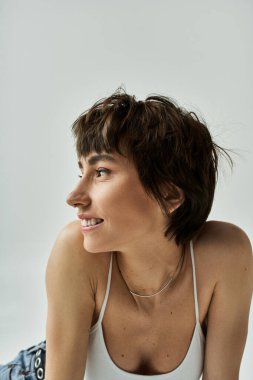 Stylish young woman in white tank top lays gracefully on floor.