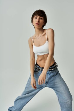 Stylish young woman in jeans and white top striking a pose.