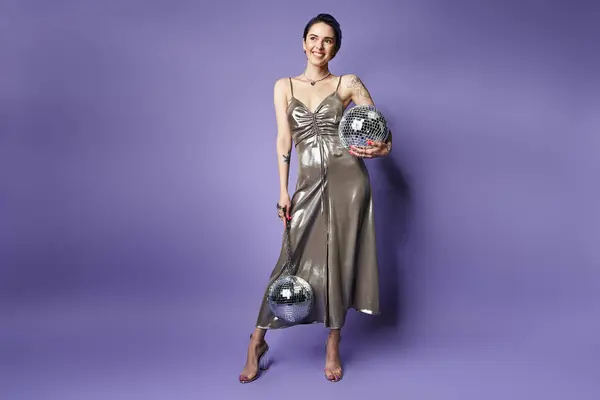 stock image A young woman with short blue hair donning a shiny silver dress, holding a dazzling disco balls.