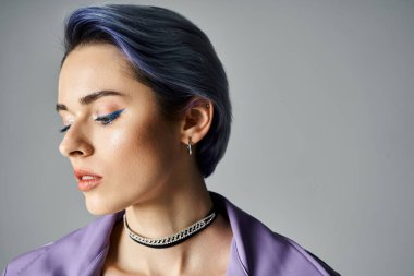 A young woman with blue hair styled in a trendy purple shirt poses confidently in a studio setting.