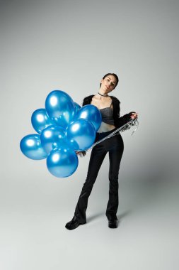 A vibrant young lady with chic style clutches a bunch of radiant blue balloons. clipart